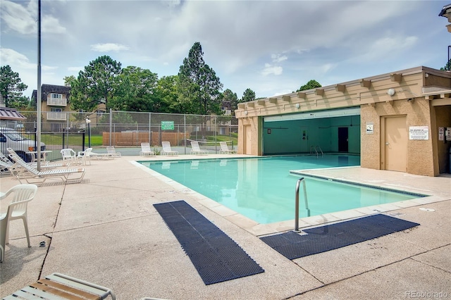community pool with a patio area and fence