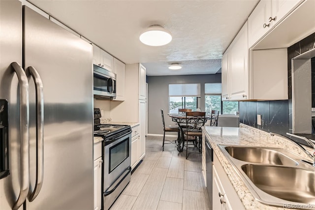 8100 W Quincy Ave Unit 11, Denver, CO 80123 - kitchen with stainless steel appliances, a sink, white cabinets, baseboards, and a textured ceiling