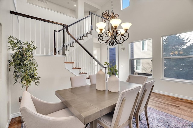 dining area featuring a notable chandelier, hardwood / wood-style flooring, and a high ceiling