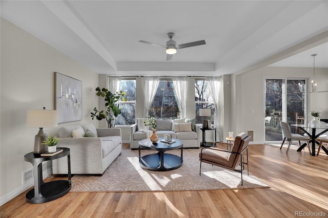 living room with wood-type flooring, a raised ceiling, and a wealth of natural light