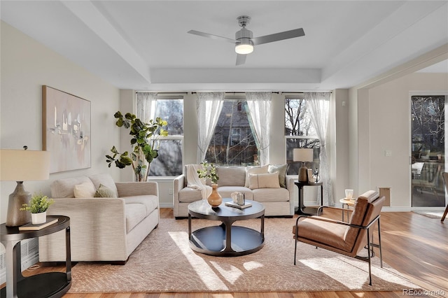 living room featuring hardwood / wood-style flooring, a healthy amount of sunlight, and a tray ceiling