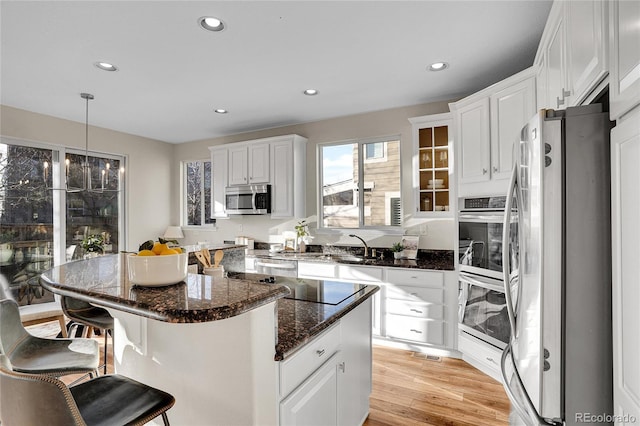 kitchen featuring a kitchen island, pendant lighting, white cabinetry, a kitchen breakfast bar, and stainless steel appliances