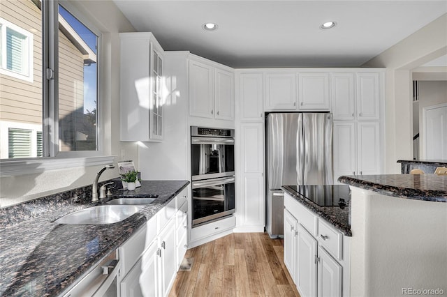 kitchen featuring white cabinetry, sink, stainless steel appliances, and dark stone countertops