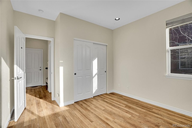 unfurnished bedroom featuring multiple windows, a closet, and light wood-type flooring