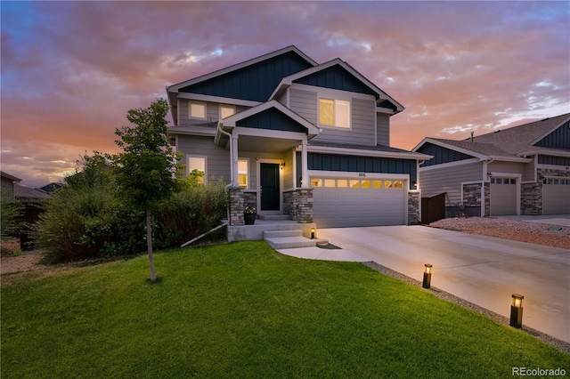 view of front of property featuring an attached garage, concrete driveway, stone siding, a lawn, and board and batten siding