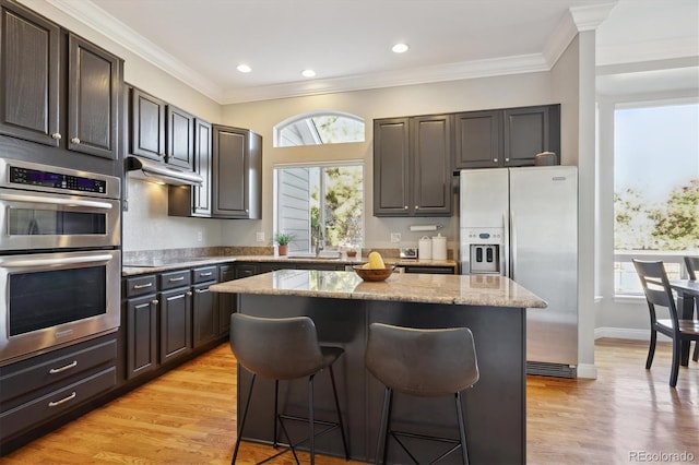 kitchen with appliances with stainless steel finishes, light hardwood / wood-style flooring, a center island, and a wealth of natural light