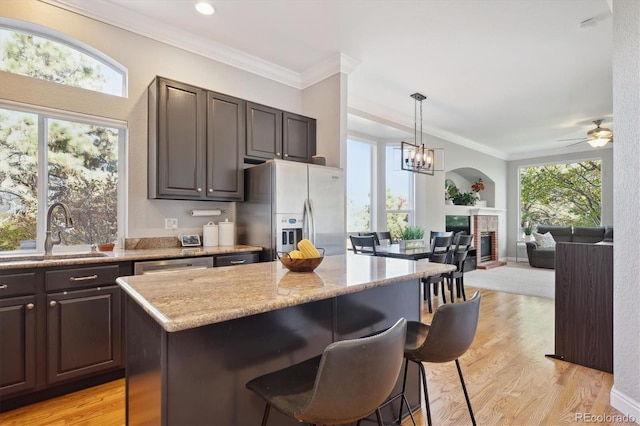 kitchen featuring sink, dark brown cabinets, stainless steel fridge with ice dispenser, and a wealth of natural light