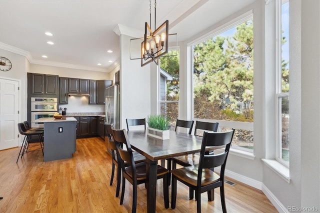 dining room featuring an inviting chandelier, crown molding, light hardwood / wood-style floors, and plenty of natural light