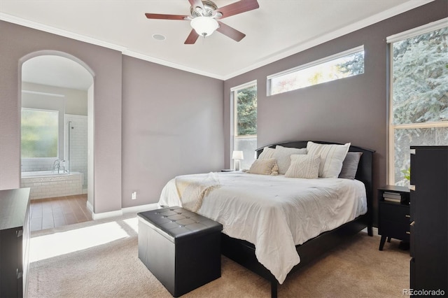 bedroom featuring ornamental molding, ensuite bathroom, multiple windows, and ceiling fan