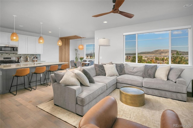 living room featuring a mountain view, sink, ceiling fan, and light hardwood / wood-style flooring