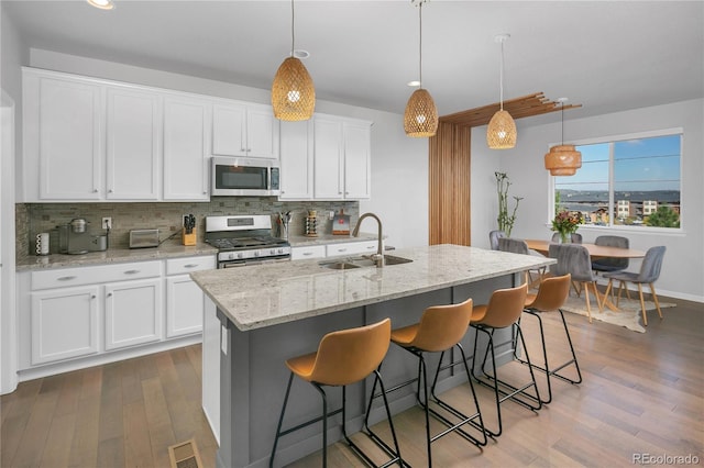 kitchen featuring white cabinetry, sink, hanging light fixtures, a kitchen island with sink, and stainless steel appliances