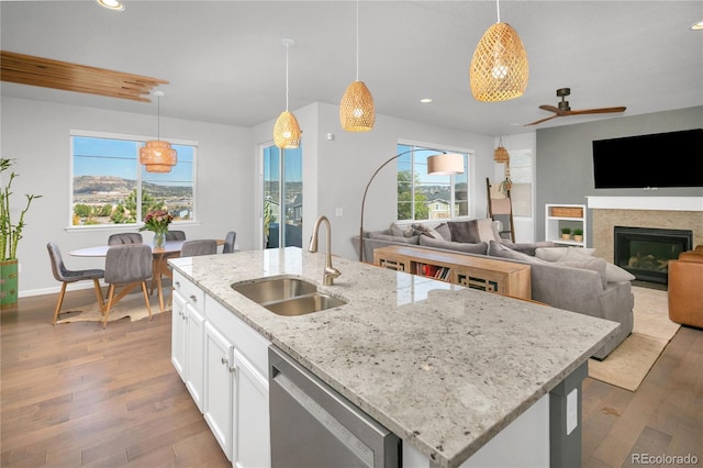 kitchen with a kitchen island with sink, sink, decorative light fixtures, and stainless steel dishwasher