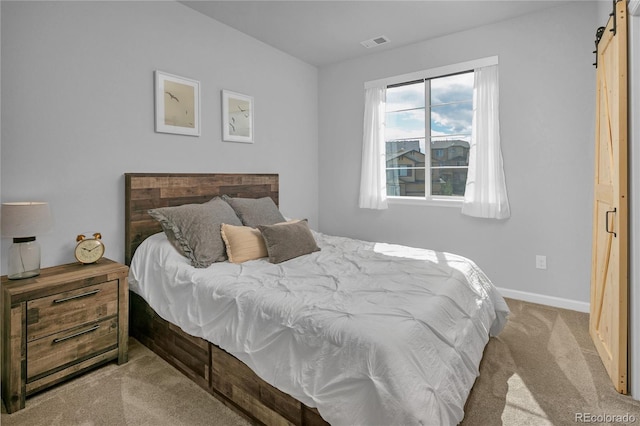 bedroom featuring light carpet and a barn door