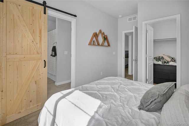 bedroom featuring light colored carpet, a barn door, and a closet