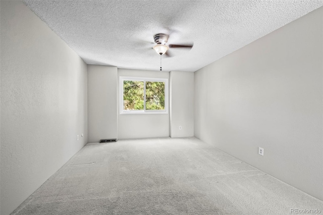 carpeted empty room with a ceiling fan and a textured ceiling