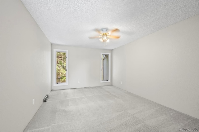spare room with light carpet, ceiling fan, and a textured ceiling