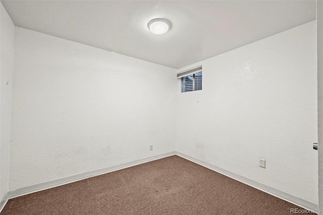 unfurnished room featuring dark colored carpet and baseboards