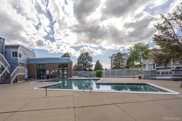 community pool with a patio and fence