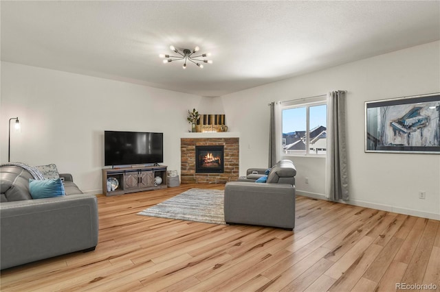 living room featuring a notable chandelier, a fireplace, and light hardwood / wood-style flooring