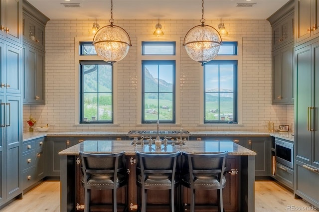 kitchen featuring a center island with sink, hanging light fixtures, a breakfast bar area, and stainless steel appliances