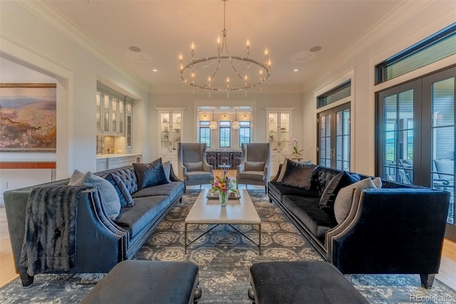 living room featuring hardwood / wood-style flooring, a chandelier, ornamental molding, and french doors