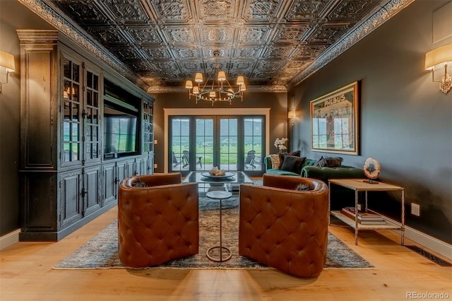 living area with light hardwood / wood-style flooring, french doors, and a notable chandelier