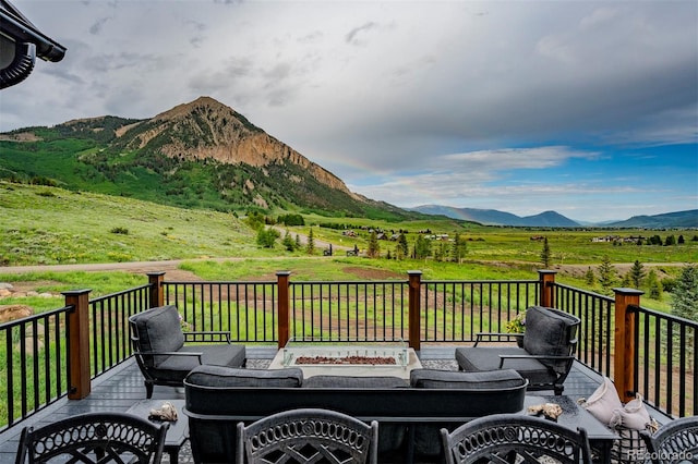 wooden terrace featuring an outdoor living space with a fire pit, a mountain view, and a rural view