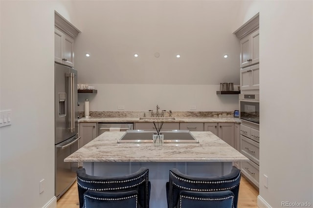 kitchen featuring a kitchen island, a kitchen bar, sink, and appliances with stainless steel finishes