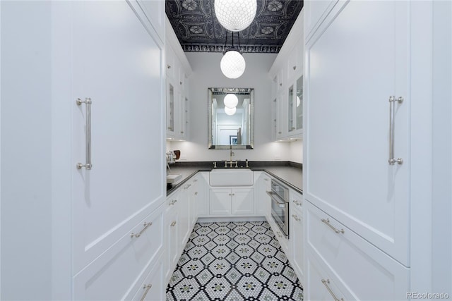 kitchen with white cabinetry, sink, oven, and hanging light fixtures