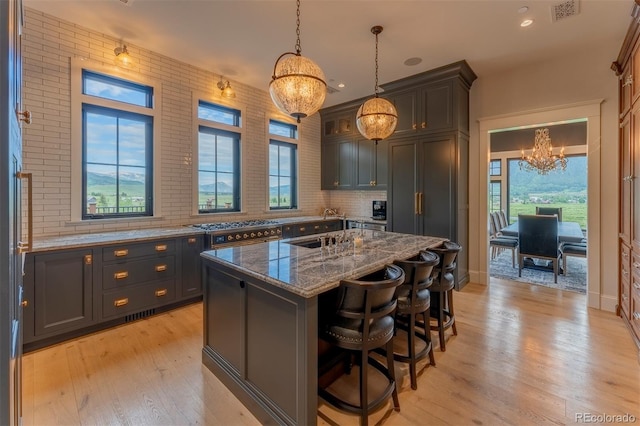 kitchen with light hardwood / wood-style flooring, a kitchen island, hanging light fixtures, and dark stone counters