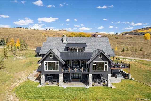 rear view of house featuring a lawn, a patio area, a wooden deck, and solar panels