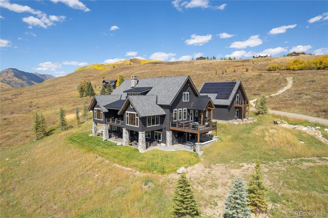921 County Road 317, Crested Butte, CO 81224 - rear view of house with solar panels, a balcony, a shingled roof, and a wooden deck