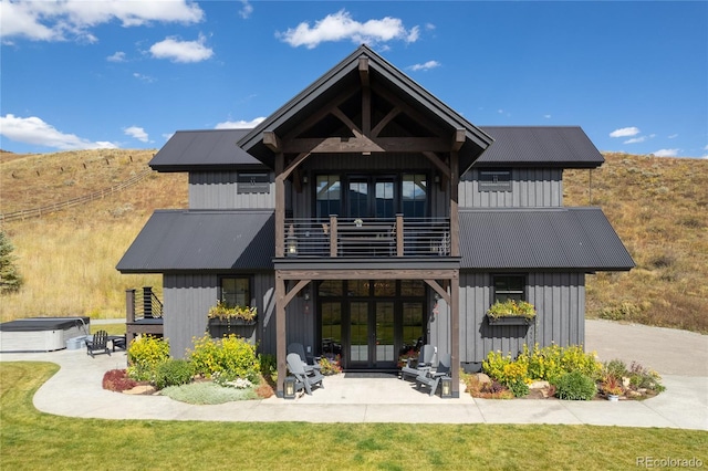 921 County Road 317, Crested Butte, CO 81224 - back of house with a balcony, french doors, a hot tub, board and batten siding, and metal roof
