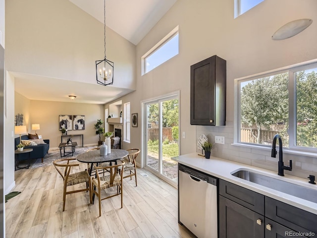 4287 Brookwood Pl, Highlands Ranch, CO 80130 - kitchen with dishwasher, high vaulted ceiling, light countertops, light wood-style floors, and decorative backsplash