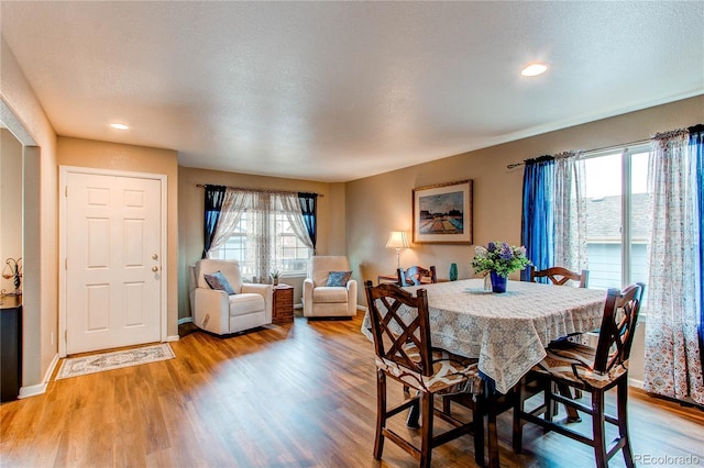 dining room featuring a textured ceiling, baseboards, and wood finished floors