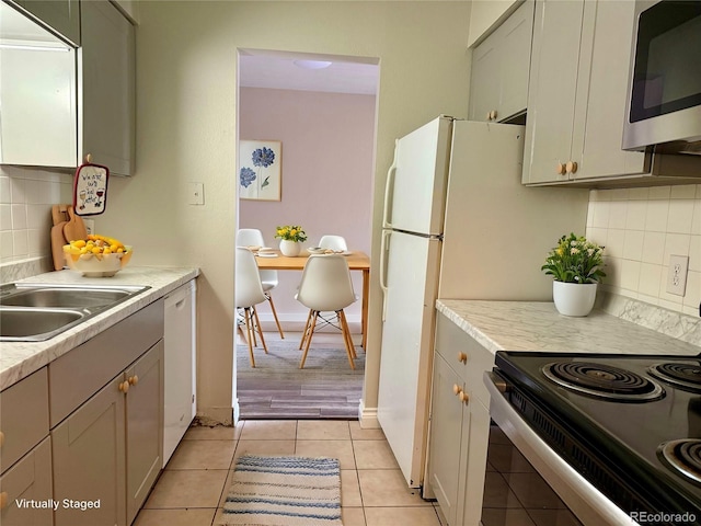 kitchen featuring backsplash, white dishwasher, sink, light tile patterned floors, and electric range