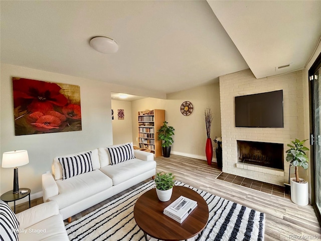 living room with wood-type flooring and a brick fireplace