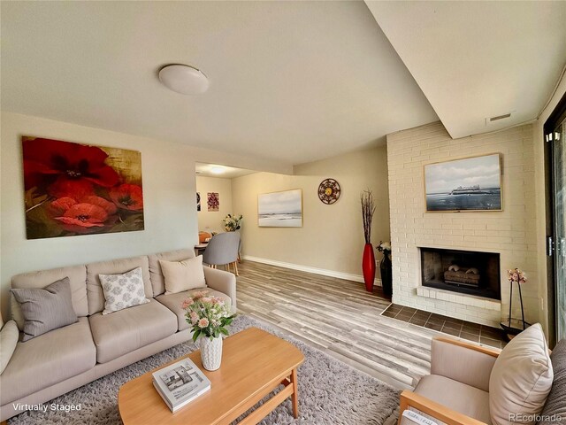 living room with wood-type flooring and a brick fireplace