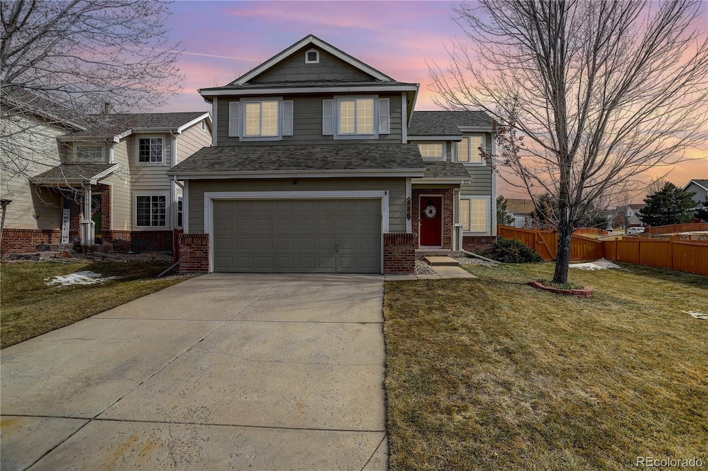 traditional-style home with fence, a yard, concrete driveway, a garage, and brick siding