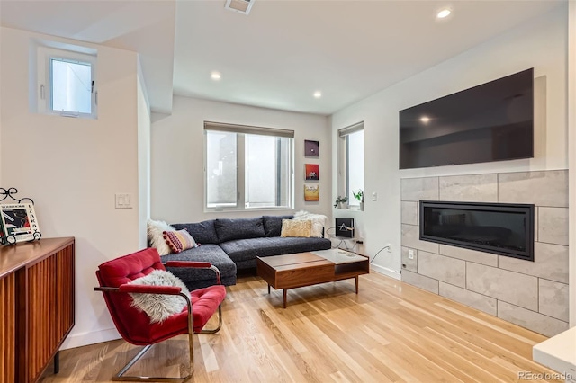 living area featuring wood finished floors, baseboards, a tiled fireplace, and recessed lighting