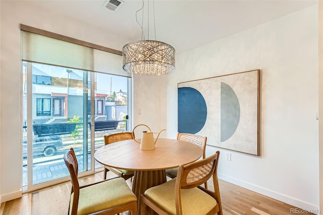 dining space featuring baseboards, light wood-style flooring, and a chandelier