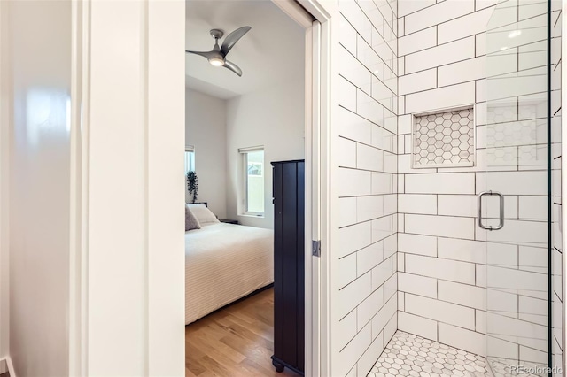 ensuite bathroom featuring a stall shower, a ceiling fan, and wood finished floors