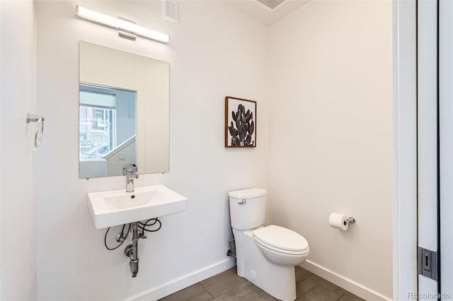 bathroom featuring toilet, baseboards, and a sink