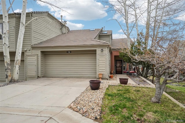 view of front of property featuring a garage, driveway, a tile roof, and a front yard