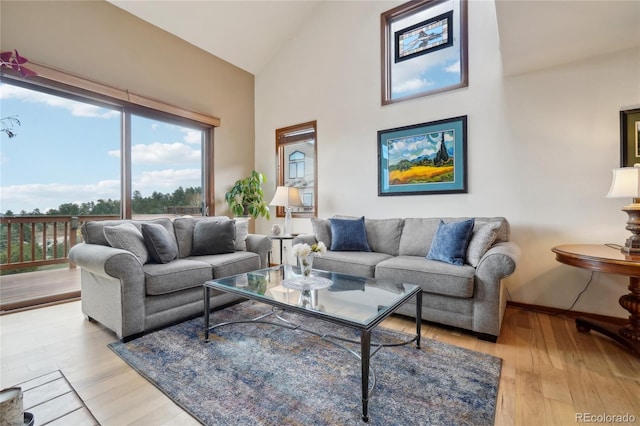 living room featuring light wood-type flooring, baseboards, a wealth of natural light, and high vaulted ceiling