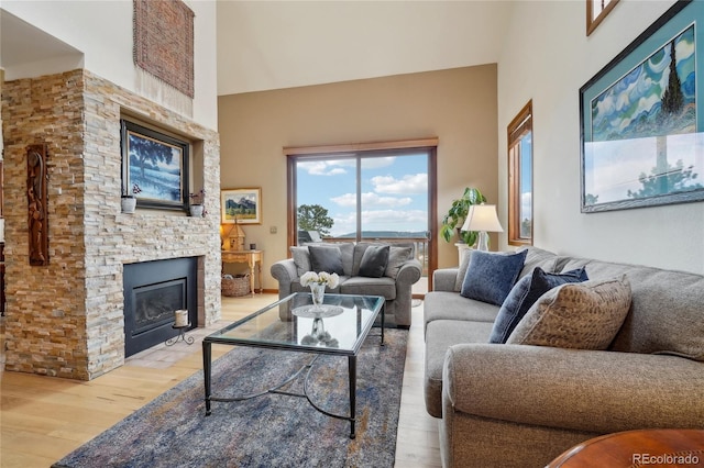 living area with a fireplace, wood finished floors, and a towering ceiling