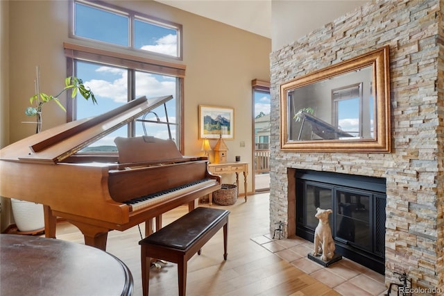 sitting room with plenty of natural light, light wood-style flooring, and a stone fireplace