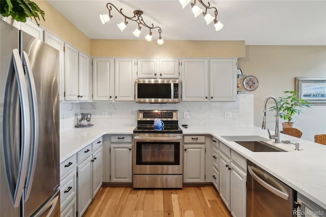 kitchen featuring backsplash, a sink, light countertops, stainless steel appliances, and light wood-style flooring