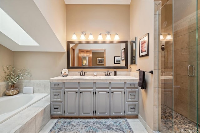 bathroom featuring double vanity, a skylight, a shower stall, and a sink
