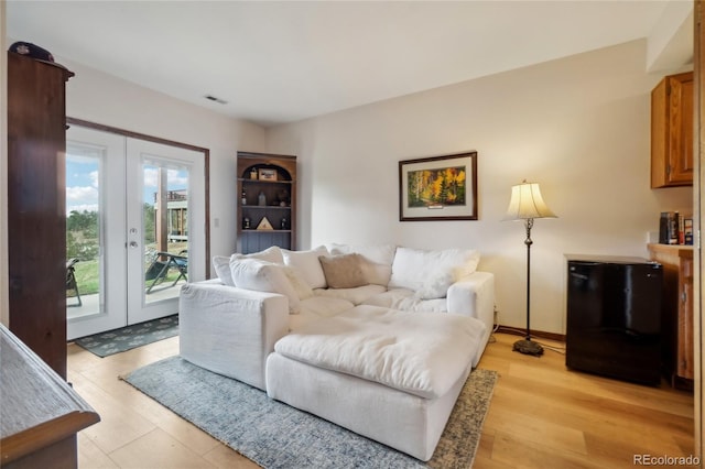 living area featuring baseboards, visible vents, french doors, and light wood-type flooring